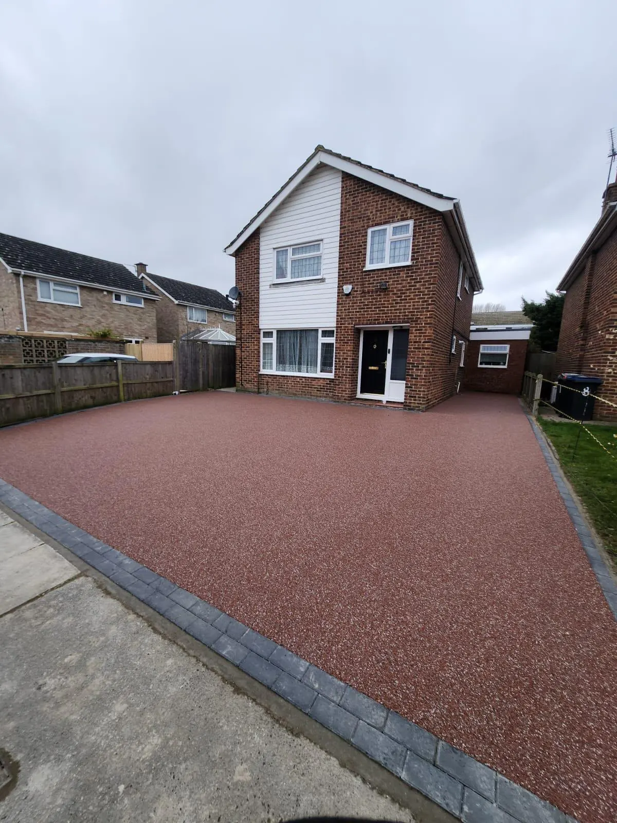 Red resin driveway outside a detached brick home